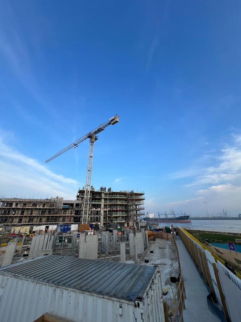 Flat-top tower crane on a riverside residential scheme beside a shipping channel