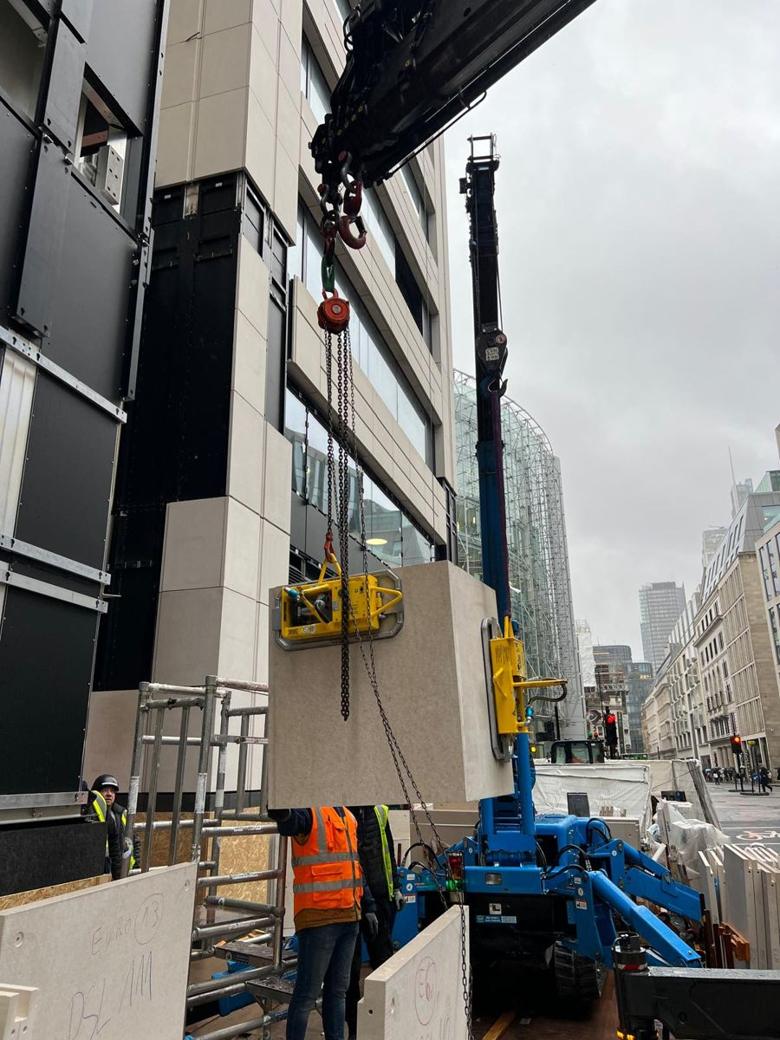 Spider crane with vacuum lifter placing a stone cladding panel